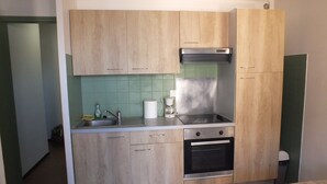 Une cuisine compacte avec des meubles en bois, une cuisinière en acier inoxydable, une machine à café et un évier.
