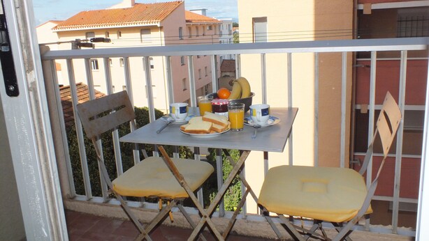 Un balcon avec une table préparée pour le petit-déjeuner, comprenant des toasts, des fruits et du jus.