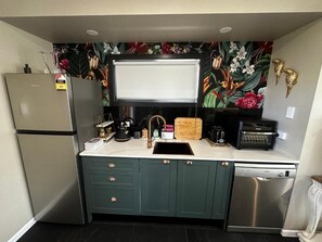 Eine kleine Küche mit Kühlschrank, Spüle, Geschirrspüler und Mikrowelle.