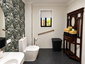 A bathroom with a toilet, sink, vanity, and a window with a view. - Hervey Bay: first-class service at Bay Bliss Haven, a unique, tranquil setting. (Point Vernon)