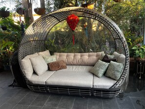 A round, woven outdoor seating area with cushions and a hanging heart ornament. - Hervey Bay: first-class service at Bay Bliss Haven, a unique, tranquil setting. (Point Vernon)