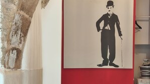 Ein Zimmer mit roter Wand, weißer Decke, einem kleinen Tisch mit Stuhl und einer Waschmaschine.
