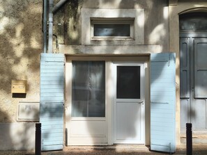 Ein Gebäudeeingang mit einer Doppeltür, einem kleinen Fenster darüber und einem Briefkasten an der Wand.