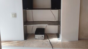 Ein Zimmer mit einer eingebauten Schrankwand, zwei Lautsprechern und einer Steuerung.