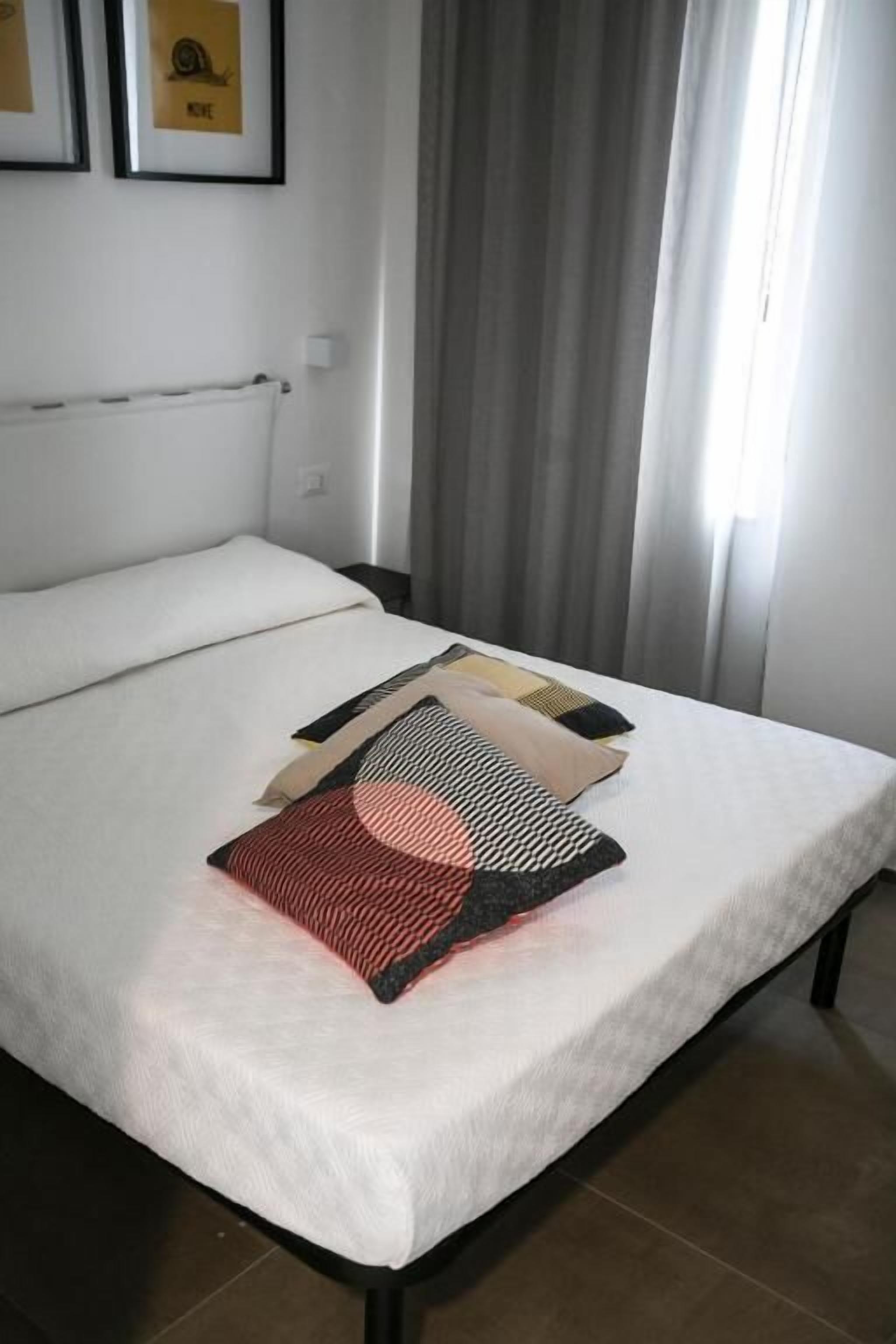Ein Bett mit weißer Bettdecke, einem gemusterten Kopfkissen und einer Decke.