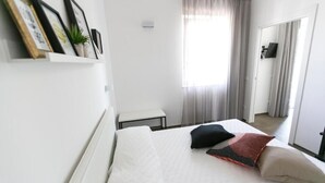 Una camera da letto con un letto, un tavolino, una pianta in vaso e uno specchio.