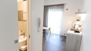 Una camera d'albergo con bagno, zona pranzo e angolo cottura.
