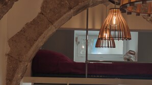 Een stapelbed met een rood kussen, een hanglamp en een raam met uitzicht op de omgeving.