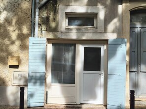 Ein Gebäude mit einer weißen Tür, einem kleinen Fenster darüber und einem blauen Rolltor.