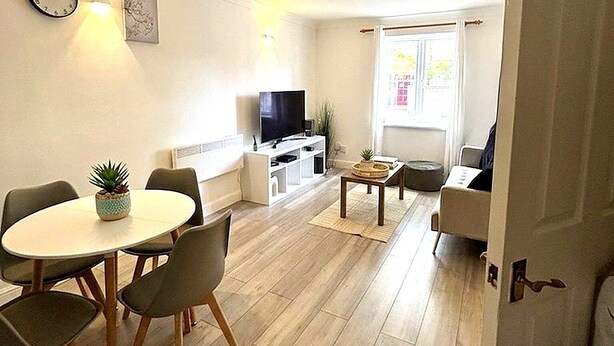 A modern living room with a dining area, a flat-screen TV, and a large window. - Modern London Stay for 5|Parking| Excel, City Airport & Canary Wharf (London)