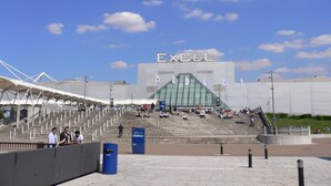 A stadium with a large 'EXCEL' sign, steps leading up to the entrance, and a clear sky. - Modern London Stay for 5|Parking| Excel, City Airport & Canary Wharf (London)