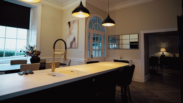 A modern kitchen with pendant lighting, a large island, and a view of the outdoors. - Bankhouse Troon, Scotland | Luxury Sea View Retreat with Hot Tub & Sauna (Troon)