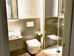 A modern bathroom with a toilet, sink, and glass-enclosed shower area. - Ground Floor Apartment (Alicante)