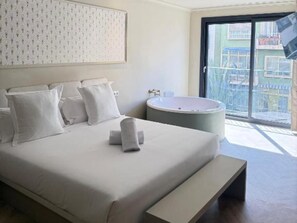 A hotel room with a large bed, a round bathtub, and a balcony with a view. - Ground Floor Apartment (Alicante)