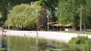 Ett område vid en sjö med en sandstrand, en liten paviljong och en rad cyklar.