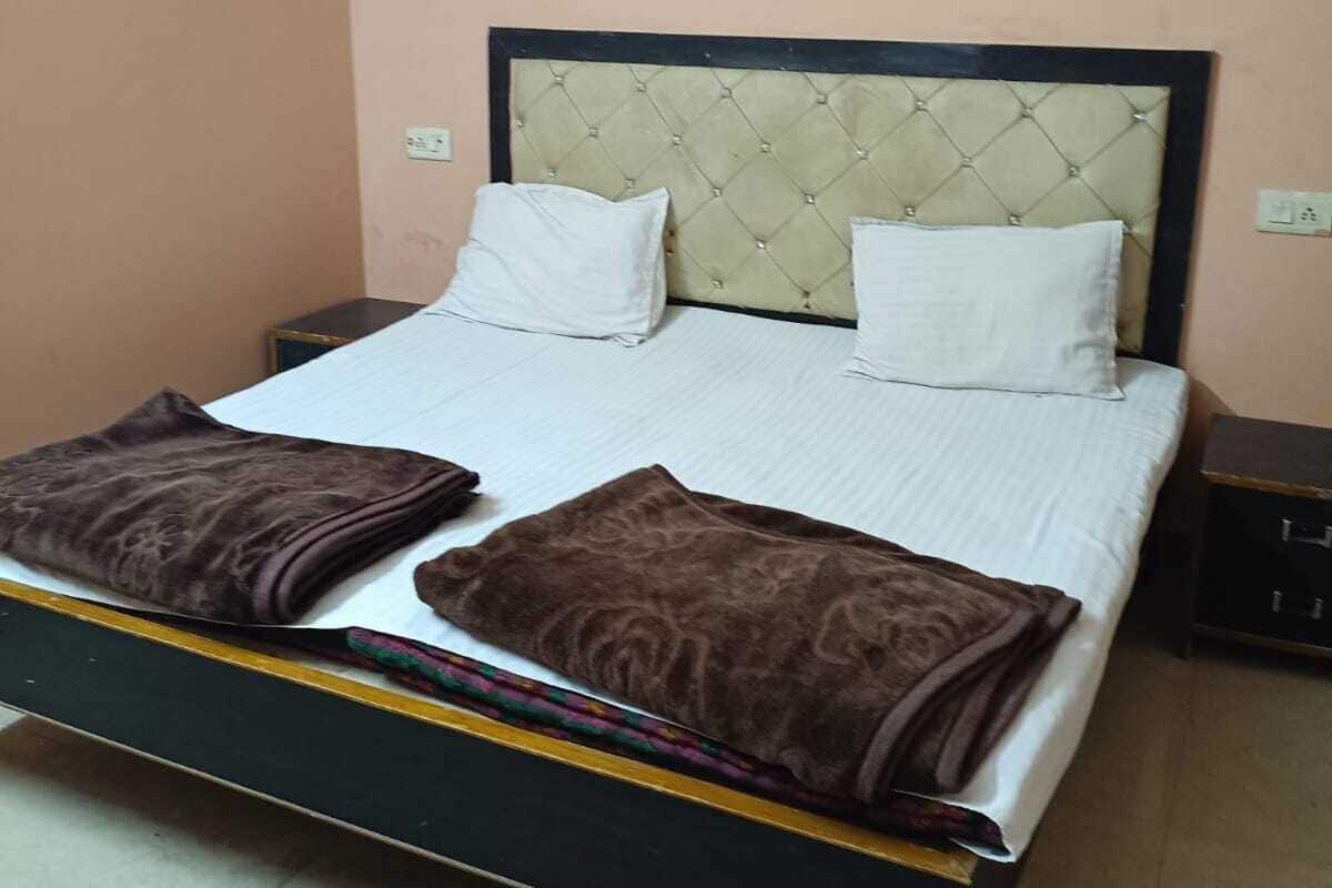 Una cama individual con cabecera capitonada, dos almohadas y dos mantas dobladas.