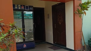 A building entrance with a checkered floor, a door with a decorative design, and potted plants. - Hotel Chaitanya Inn  (Varanasi)