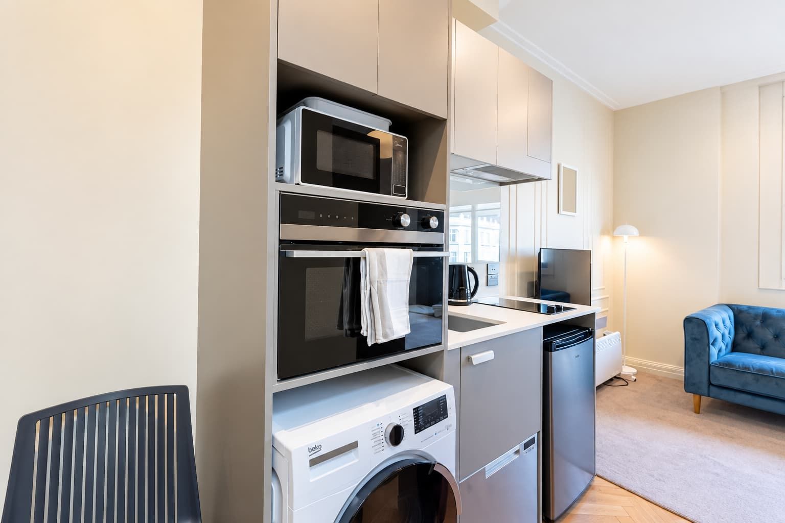 A compact kitchenette with a microwave, oven, and built-in washing machine.