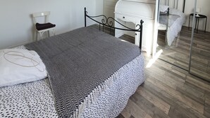A bedroom with a bed, a chair, a TV, a mirror, and a painting on the wall. - Three rooms at "Chez Valou & Mika" in Mont de Marsan, Landes. (Mont-de-Marsan)