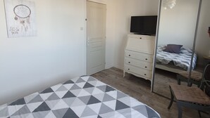A bedroom with a bed, dresser, TV, and a mirror. - Three rooms at "Chez Valou & Mika" in Mont de Marsan, Landes. (Mont-de-Marsan)
