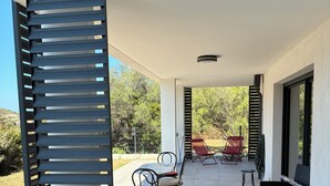 Un patio couvert aménagé avec du mobilier d’extérieur, notamment des chaises et une table, et offrant une vue sur le paysage environnant.
