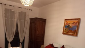 Une chambre à coucher avec un lit, une armoire en bois, un tableau au mur et un luminaire suspendu.