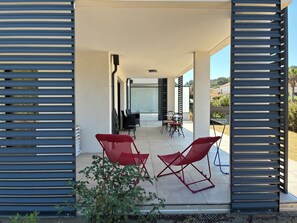 An outdoor patio area with a table and chairs, a view of the surrounding landscape, and a modern architectural design. - Summer rentals by the sea in South Corsica (Propriano)