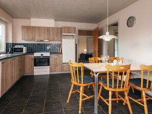 Una cocina moderna con armarios de madera, horno empotrado y comedor con sillas y mesa de madera.