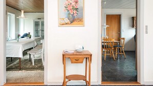 Ein Zimmer mit Essbereich, einem Tisch mit Blumenvase und einem Gemälde an der Wand.