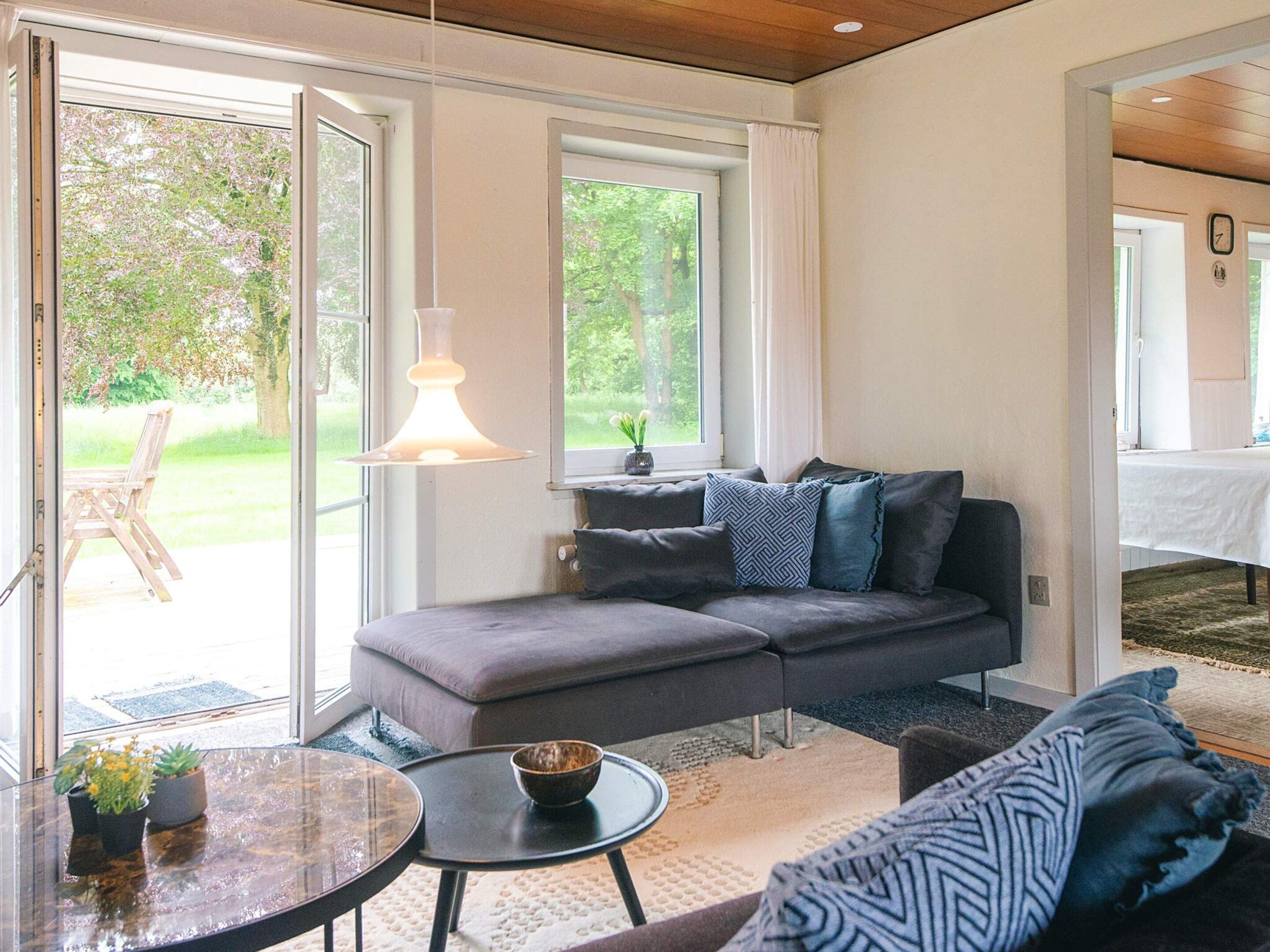 A modern living room with a grey sofa, a round coffee table, and a hanging light fixture.