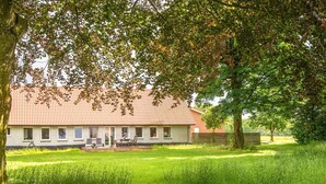 Ein Haus mit rotem Dach, einer Veranda und einem grünen Garten.