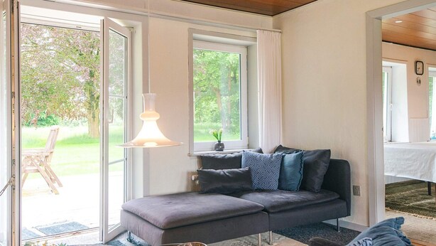 Ein modernes Wohnzimmer mit einem grauen Sofa, einem runden Tisch und einer Pendelleuchte.
