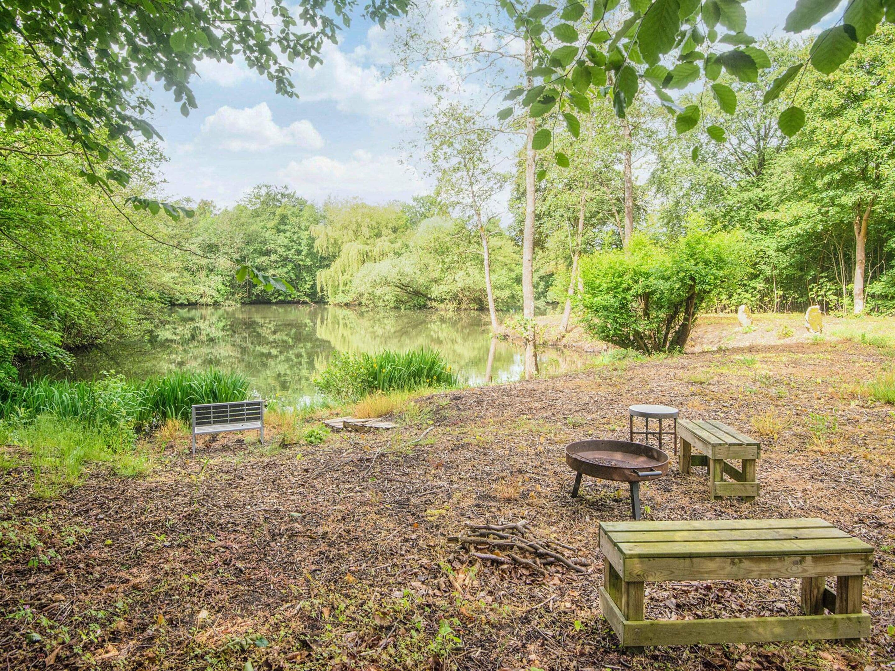 A lakeside campsite with a bench, picnic table, and fire pit.