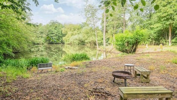 A lakeside campsite with a bench, picnic table, and fire pit.