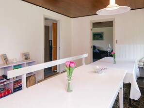 A room with a white table, a vase with flowers, and a bookshelf.