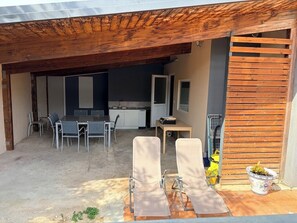 An outdoor patio with a dining table and chairs, a wooden pergola, and a potted plant. - Very quiet, renovated 58 m2 apartment 100m from the sea (La Seyne-sur-Mer)