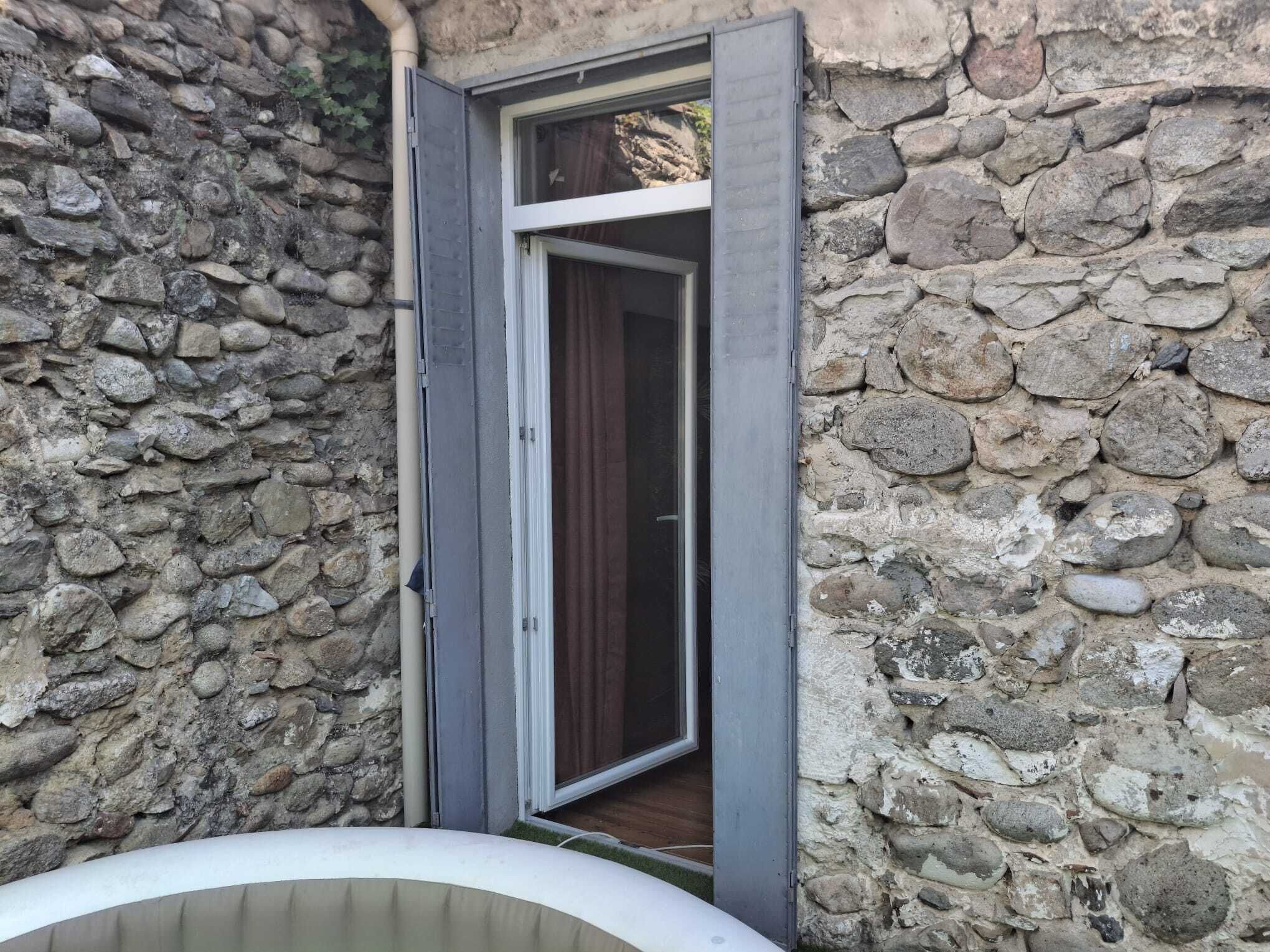 A stone wall with a door leading to a room.