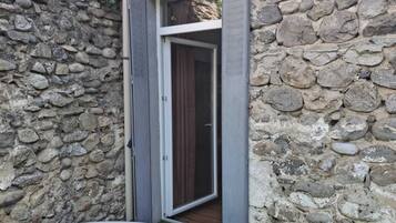 A stone wall with a door leading to a room.