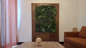 Una habitación con una mesa de centro de madera, un sofá y una pared cubierta de jardín vertical.