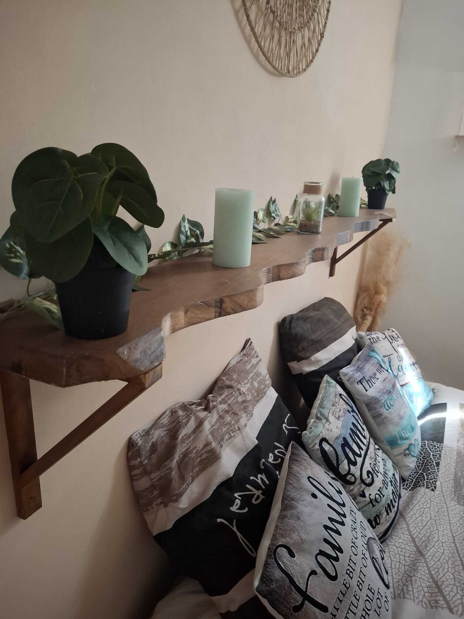 A shelf with a potted plant, candles, and decorative items.