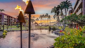 A hotel with a pool, palm trees, and a sunset view. - 1BR ocean-view condo in West Maui with pool, hot tub, kitchen-Papakea F210 (Lahaina)