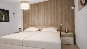 Uma cama de casal com cabeceira de madeira, mesas de cabeceira com abajures e um quadro pendurado na parede.