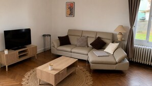 A modern living room with a sofa, TV, wooden coffee table, and a woven rug. - Entre Rails & Rives (Montbard)