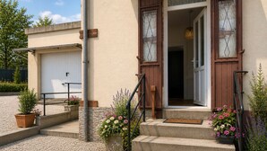 A house with a garage, a staircase leading to the entrance, and potted plants. - Entre Rails & Rives (Montbard)