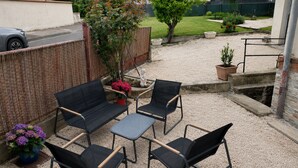 An outdoor patio with a black metal table and four chairs, surrounded by gravel. - Entre Rails & Rives (Montbard)