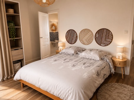 A bedroom with a wooden bed, bedside lamps, a wall-mounted mirror, and a shelf with a plant.. Entre Rails & Rives