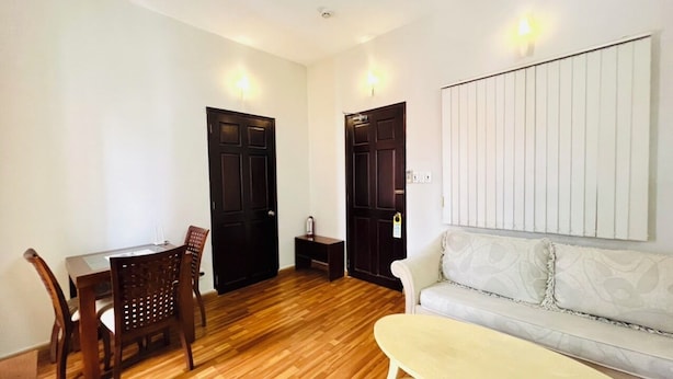 A room with a wooden floor, a dining table with chairs, a sofa, and two doors. - 1-bedroom apartment windows, balcony, full kitchen, Bathtub in Ho Chi Minh City (Ho Chi Minh City)