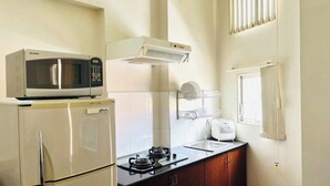 A compact kitchen with a microwave, stove, and a small sink. - 1-bedroom apartment windows, balcony, full kitchen, Bathtub in Ho Chi Minh City (Ho Chi Minh City)