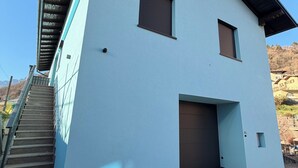 En toetages bygning med lyseblå facade, en overdækket trappe og indkørsel.