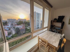 Une piĂšce avec une grande fenĂȘtre, une table Ă manger et une chaise.